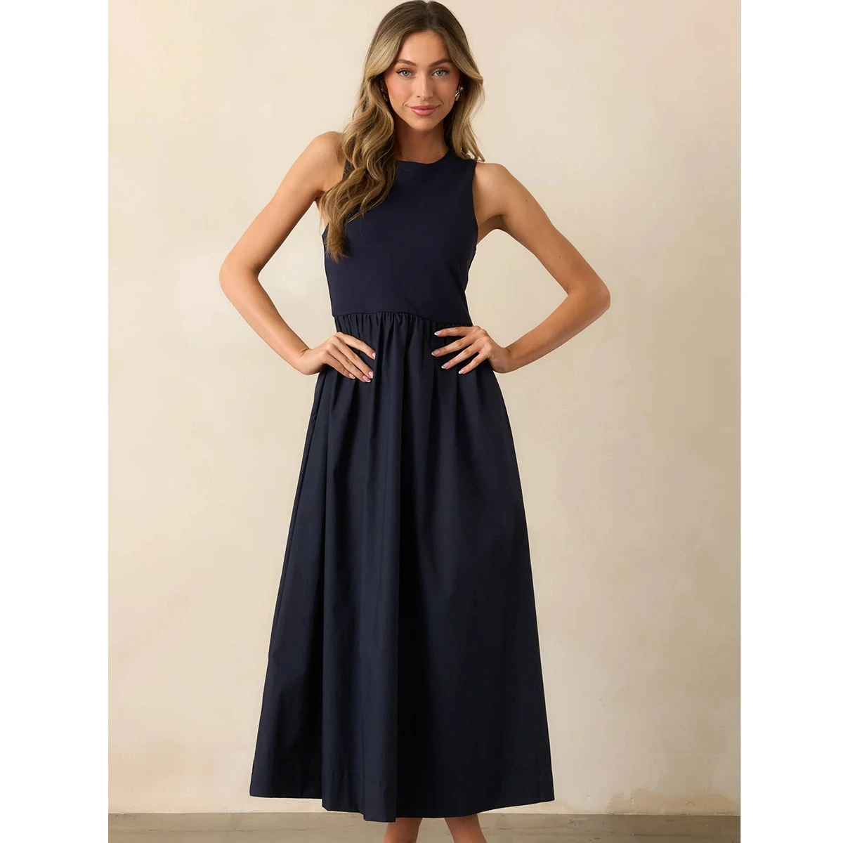 navy sleeveless maxi dress with crew neckline, fitted bodice, gathered waist, side pockets and loose a-line wide skirt silhouette